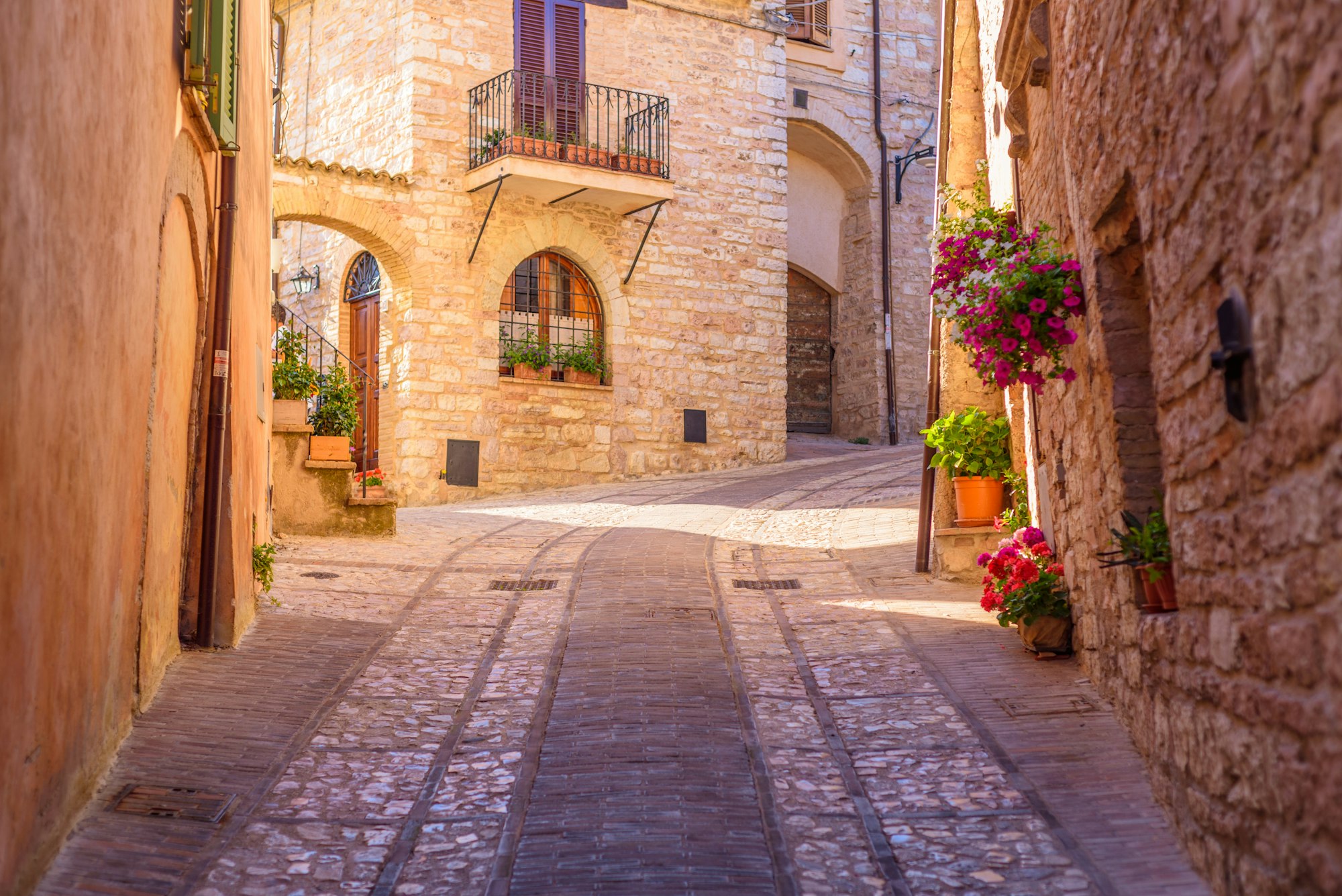 Beautiful view of an alley with stone buildings decorated with the flowers in Spello, Italy